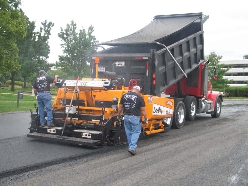 two men working with a road paving machine